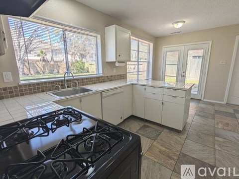 A kitchen with a black stove top and white cabinets.