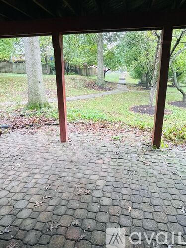 A patio with a brick floor and a view of a backyard.