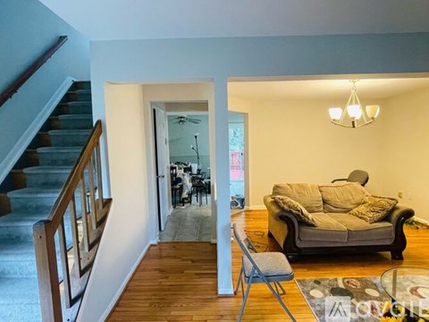 A living room with a grey couch and a wooden staircase.
