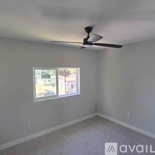 A room with a ceiling fan and a window showing an outdoor view.