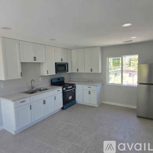 A kitchen with white cabinets and a stainless steel refrigerator.