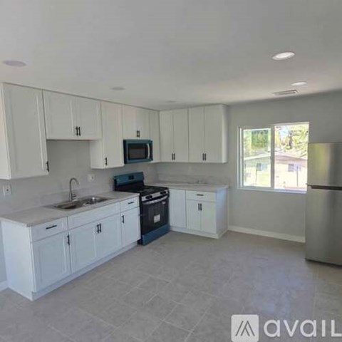 A kitchen with white cabinets and a stainless steel refrigerator.