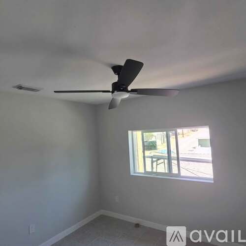 A room with a ceiling fan and a window.