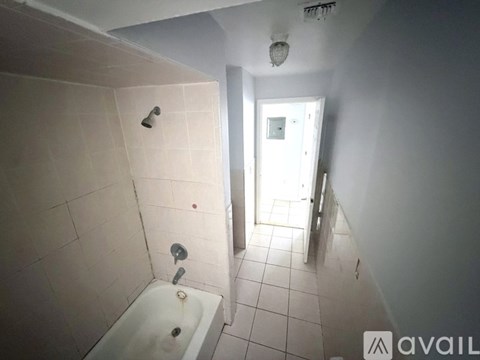 A bathroom with a white bathtub and tiled floor.