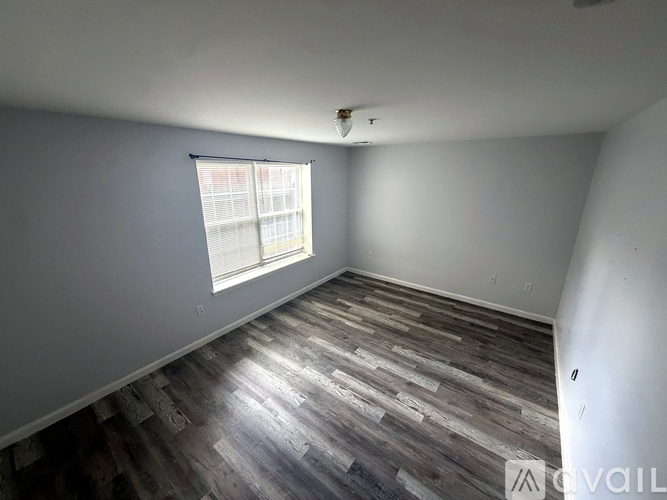 A room with wooden flooring and a window with blinds.