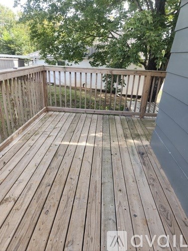 A wooden deck with a railing and trees in the background.