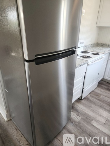 A stainless steel refrigerator with a black handle is in a kitchen.