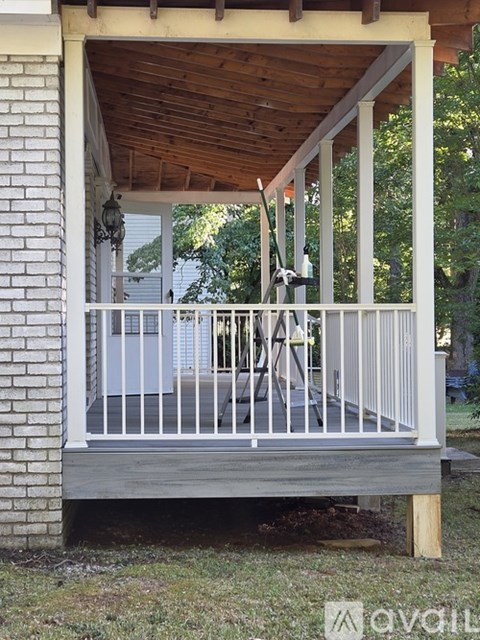 A wooden deck with a white railing and a ceiling fan.