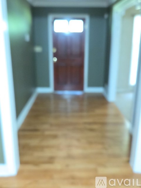 A hallway with a wooden floor and a red door.