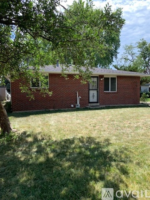 A red brick house with a tree in front.