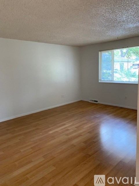 Empty room with wooden flooring and a window.