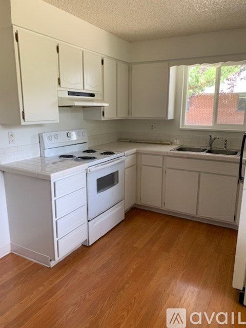 A kitchen with white cabinets and a wooden floor.