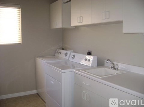 A white bathroom with a sink and a washer and dryer.