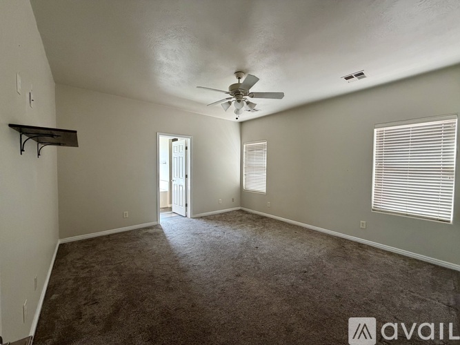 A spacious room with a ceiling fan and carpeted floor.
