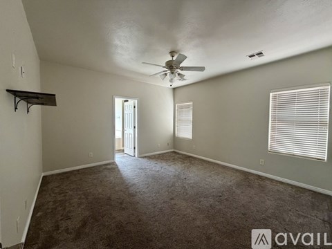 A spacious room with a ceiling fan and carpeted floor.