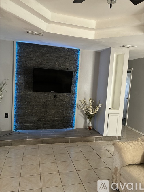 A living room with a flat screen TV mounted on a stone wall.