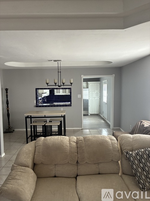 A living room with a couch, a television, and a chandelier.