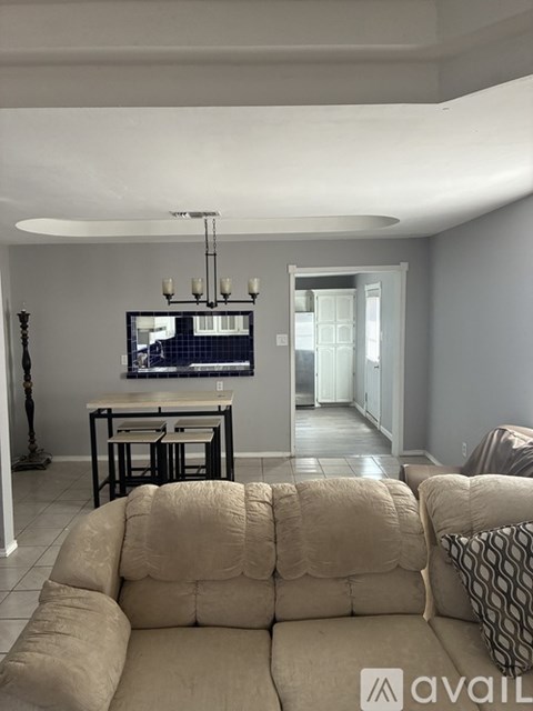 A living room with a couch, a television, and a chandelier.