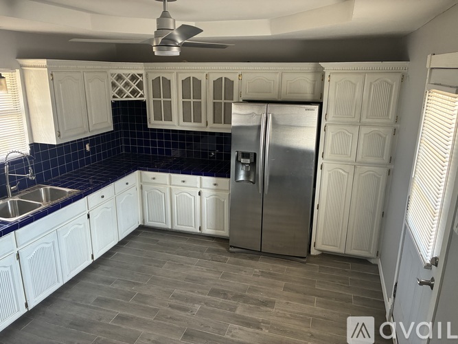 A kitchen with white cabinets and a blue tile backsplash.