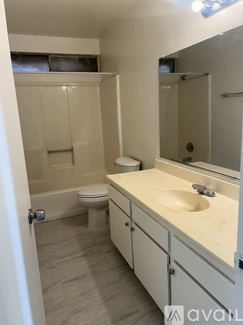 A bathroom with a toilet, sink, and mirror.