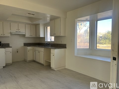 A kitchen with white cabinets and a window.