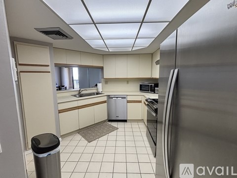 A kitchen with a trash can and a refrigerator.