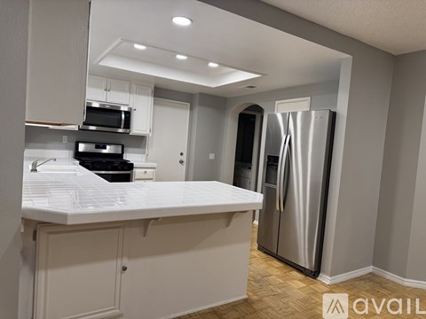 A modern kitchen with a stainless steel refrigerator and white countertops.