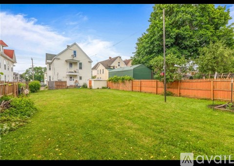 A backyard with a green lawn and a fence.