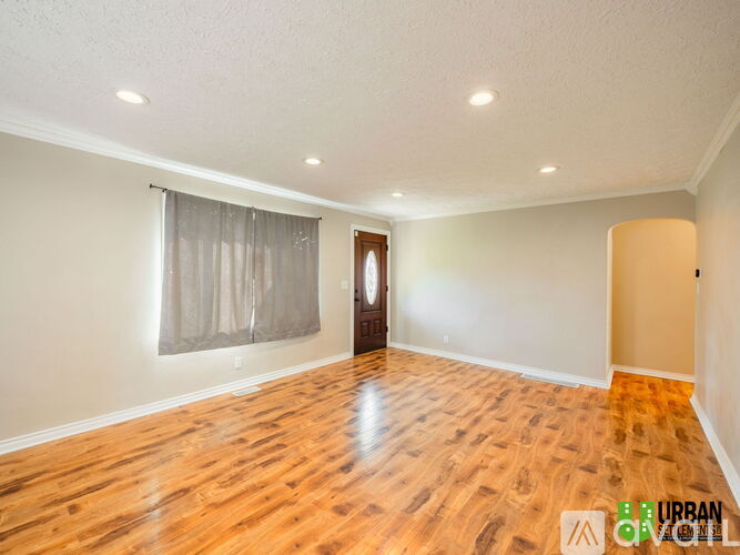 A room with wooden flooring and a window with curtains.
