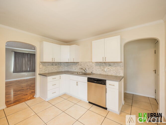 A kitchen with white cabinets and a marble countertop.