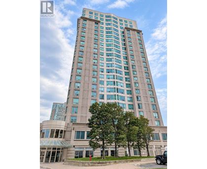 A tall building with a glass facade stands under a blue sky.