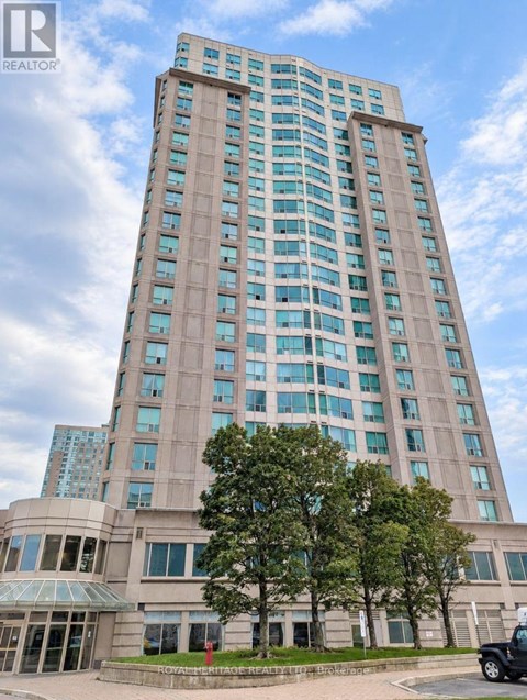 A tall building with a glass facade stands under a blue sky.
