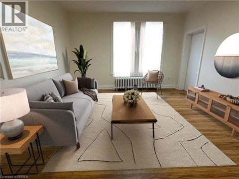 A living room with a grey couch, a wooden coffee table, and a large window with white curtains.