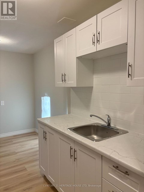 A kitchen with white cabinets and a marble countertop.