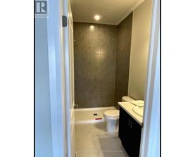 A bathroom with a toilet, sink, and tiled walls.