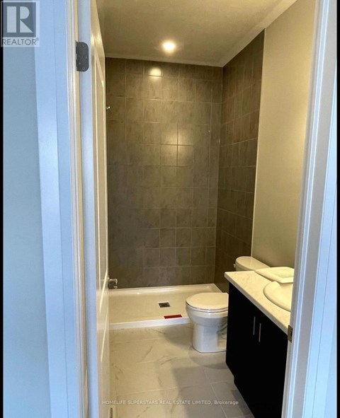 A bathroom with a toilet, sink, and tiled walls.