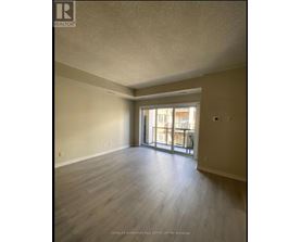 A spacious room with wooden flooring and a sliding glass door leading to a balcony.