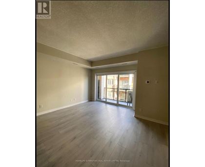 A spacious room with wooden flooring and a sliding glass door leading to a balcony.