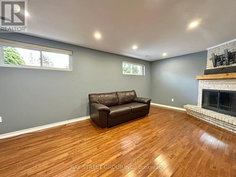 A living room with a brown leather couch and a fireplace.
