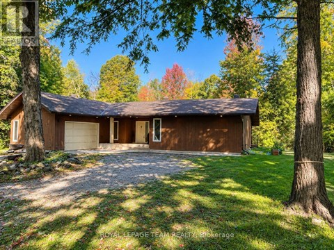 A house with a brown roof and a gravel driveway in front of it.