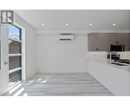 A spacious, empty room with a window, a white countertop, and a built-in oven.