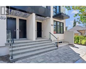 A modern house with a glass entrance and a staircase leading to the door.