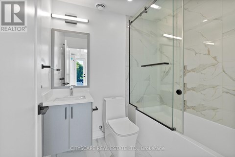 A white bathroom with a marble wall and a glass shower door.