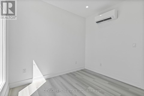 A white room with a window and a wall-mounted air conditioner unit.