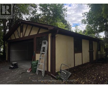 A garage with a ladder and a brokerage sign.