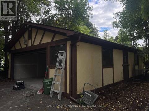 A garage with a ladder and a brokerage sign.