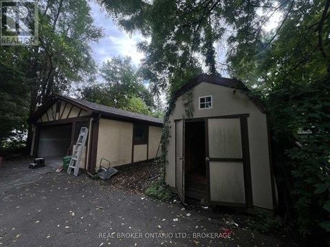 A small building with a door open is surrounded by trees.