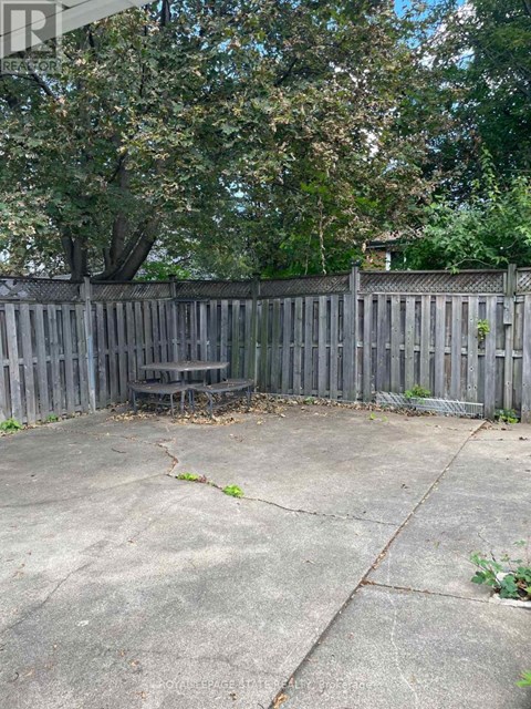 A concrete patio with a wooden fence and a tree in the background.