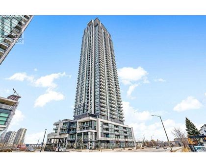 A tall building with many windows stands in front of a blue sky with clouds.