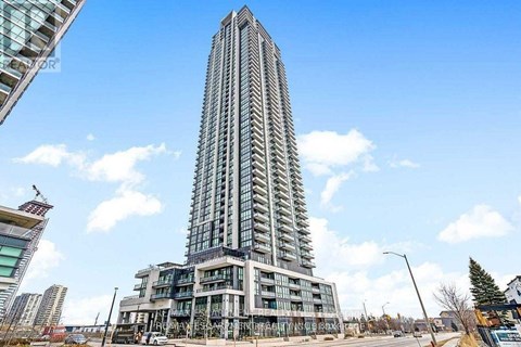 A tall building with many windows stands in front of a blue sky with clouds.